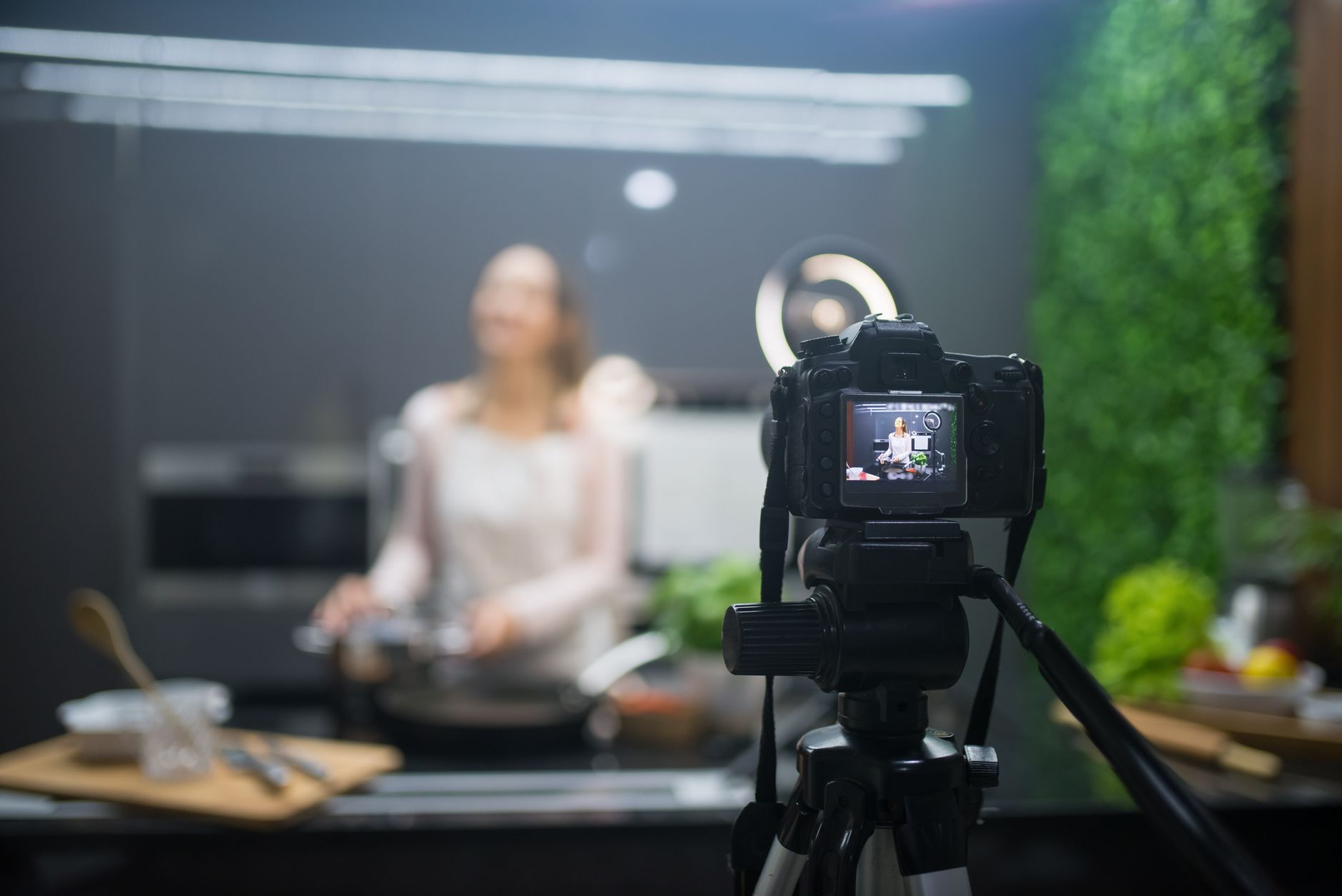 Behind the scenes of a cooking show setup with camera and tripod capturing the chef.