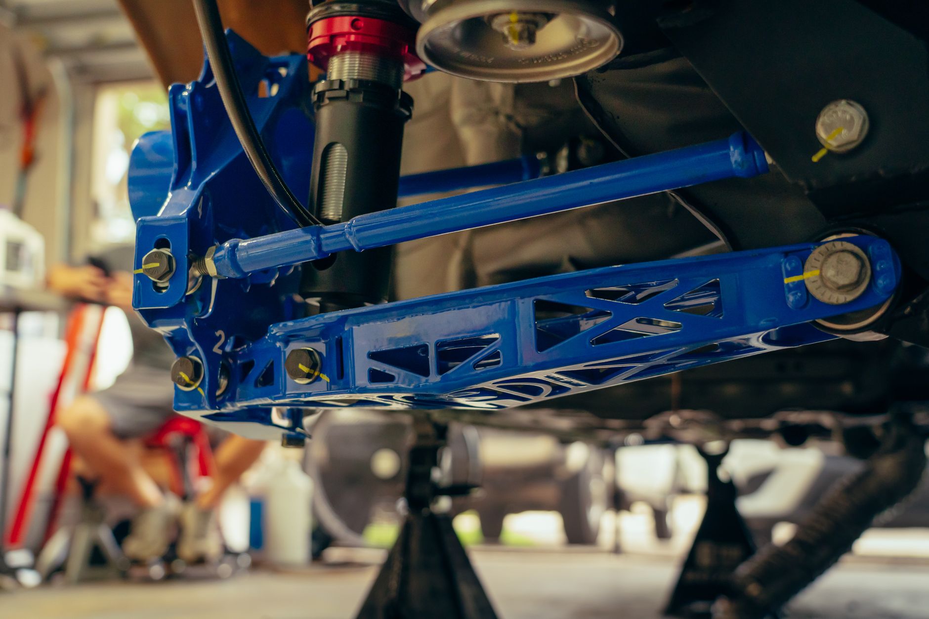 Detailed view of a blue custom car suspension part in an auto garage.