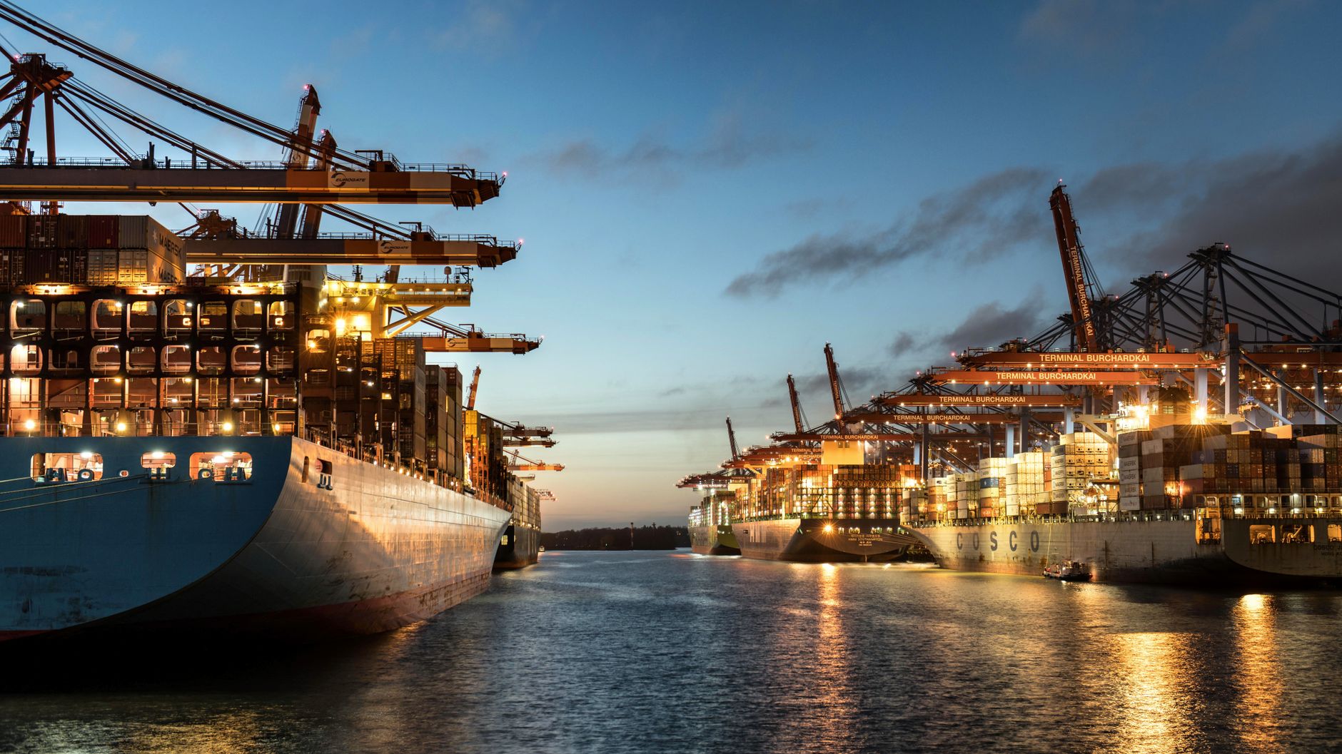 A scenic view of container ships moored at Hamburg harbor during sunset, highlighting logistics and shipping operations.