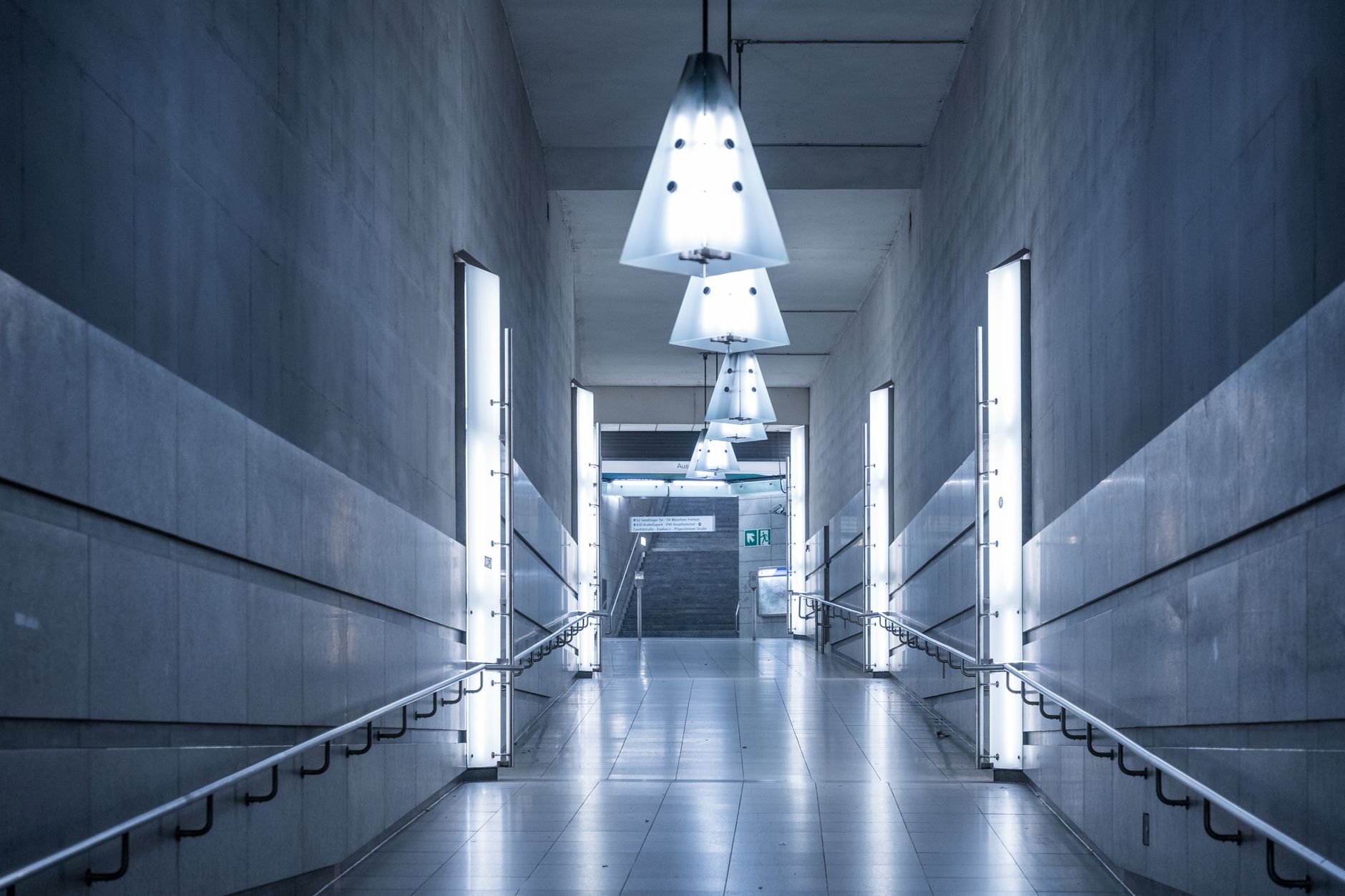 Explore a sleek, illuminated subway corridor with modern design elements and a calming blue tone.