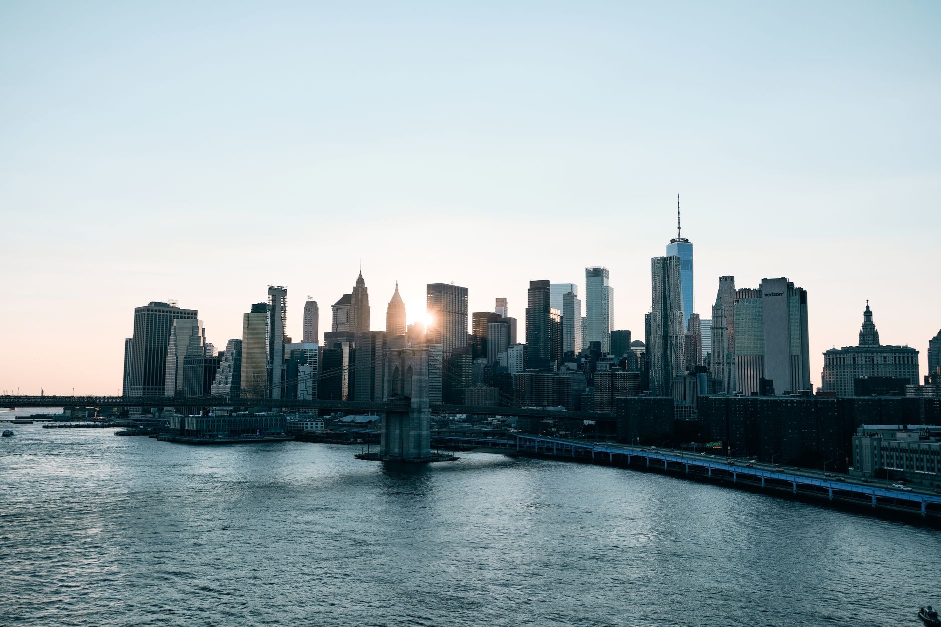 Stunning view of New York City's skyline with skyscrapers and river at sunrise.