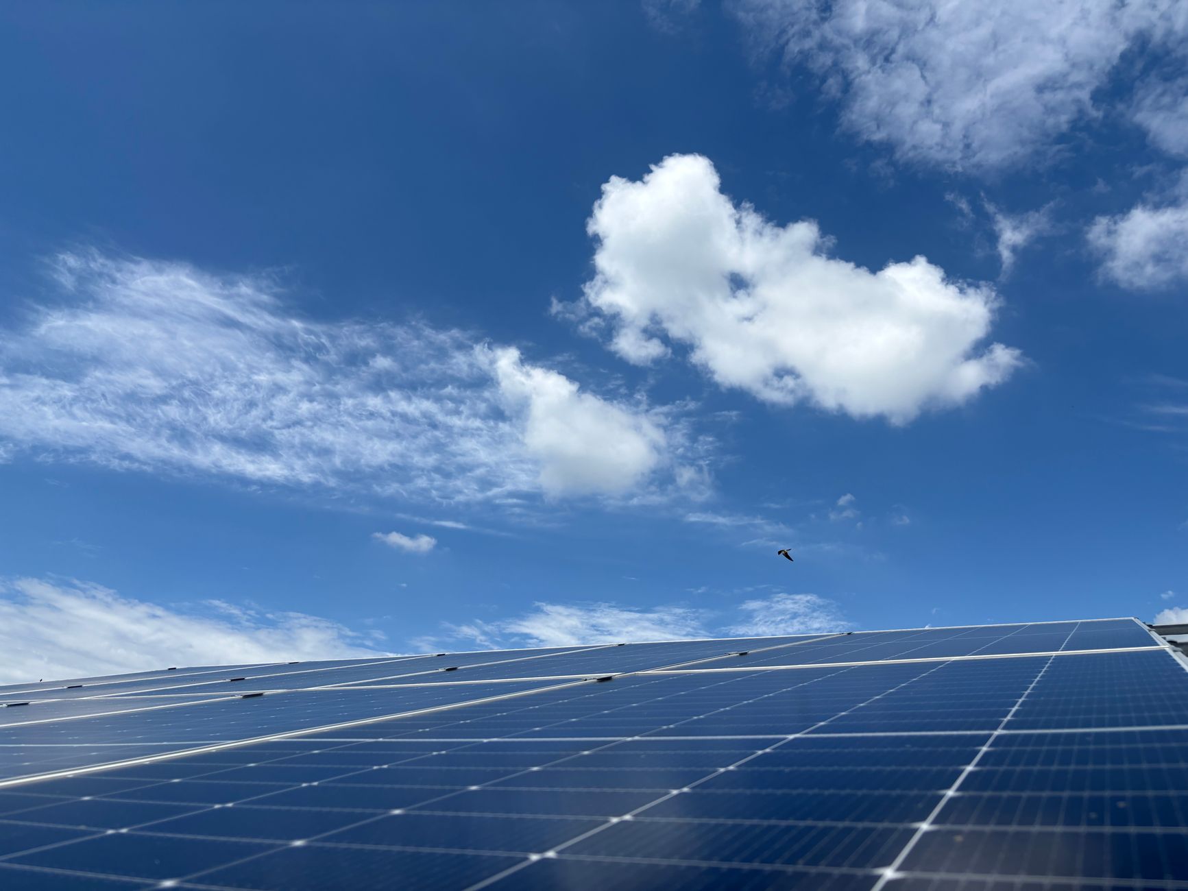 Solar panels with clear blue sky and clouds in Dehradun, India. Sustainable energy captured.