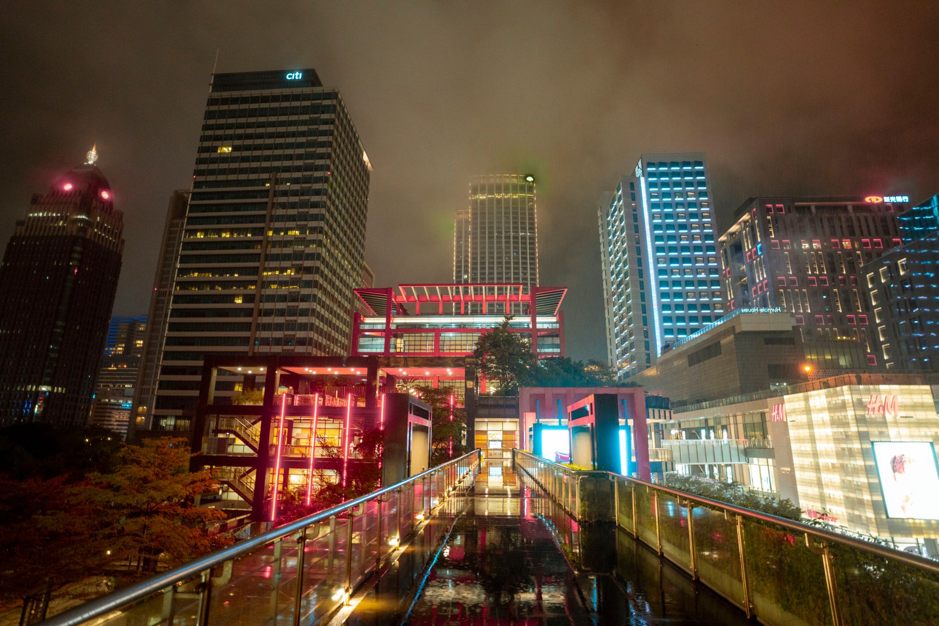 Capture the vibrant energy of a bustling city at night with illuminated skyscrapers and modern architecture.